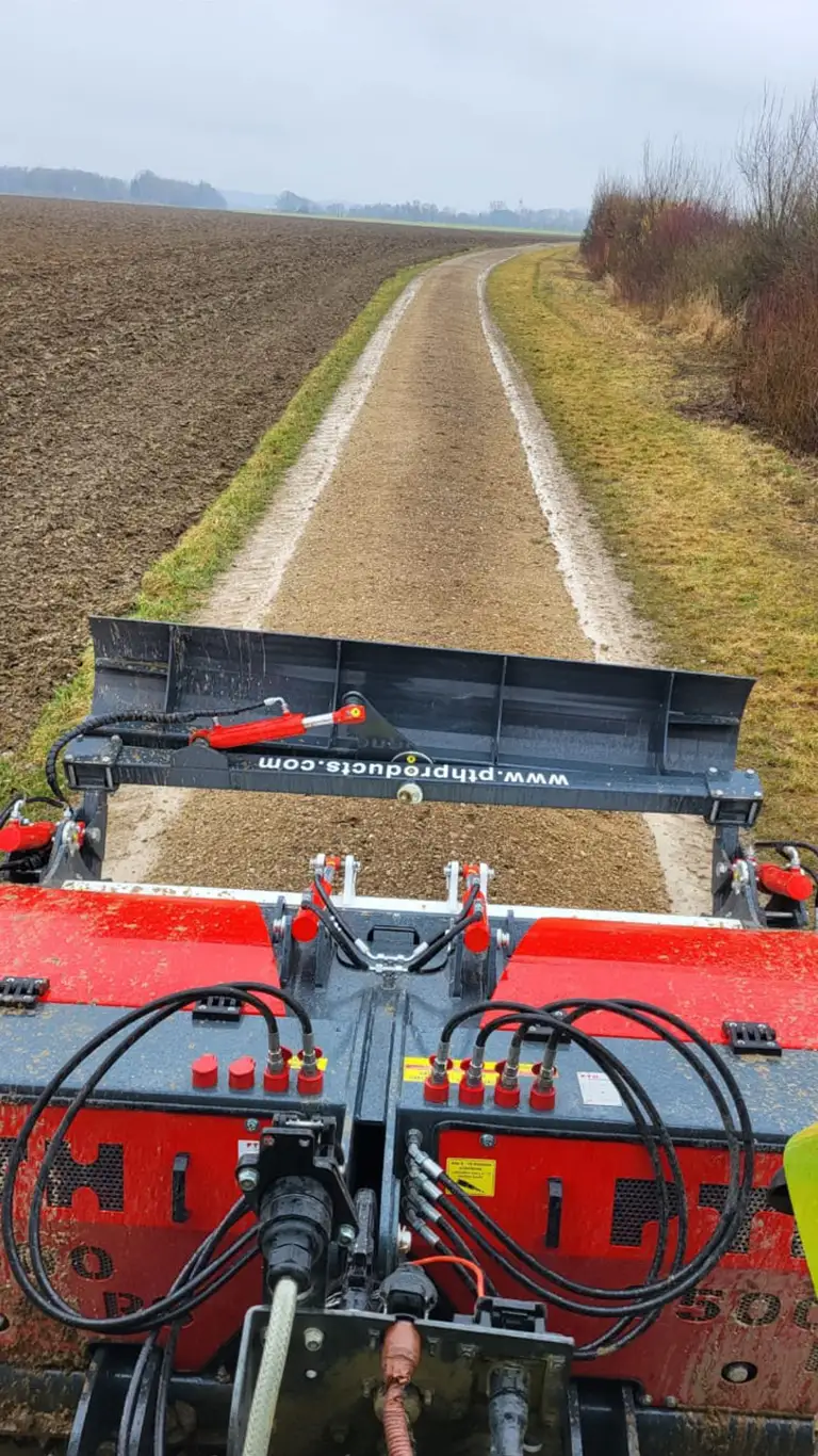 Wegepflegefräse arbeitet sich über den Feldweg